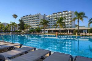 a large swimming pool with lounge chairs and a hotel at Hotel Puerto Bahía & Spa in El Puerto de Santa María