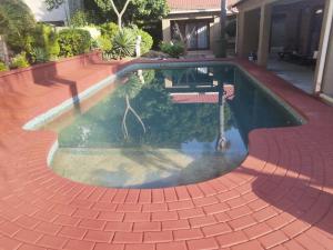 a swimming pool with a brick walkway around it at Stay & unwind in Alberton
