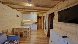 a kitchen and dining room with a table and a television at Fraseryja domek w Bieszczadach in Bukowiec