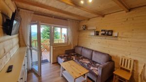 a living room with a couch and a balcony at Fraseryja domek w Bieszczadach in Bukowiec
