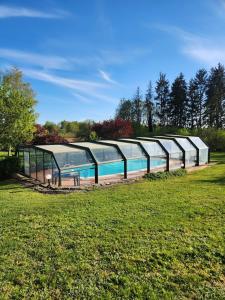 a greenhouse with a swimming pool in a field at Les Vergnes in Saint-Pardoux-le-Neuf