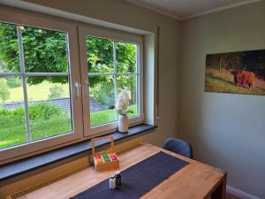 a room with a wooden table and two windows at Ferienwohnung Talblick in Schmallenberg