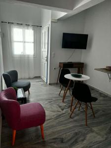a living room with chairs and a table and a television at Grecos in Perissa