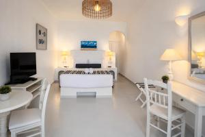 a white living room with a white couch and a tv at Santorini Theasis Suites in Imerovigli