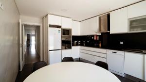a kitchen with white cabinets and a table and chairs at Moradia T4 Fernão Ferro in Fernao Ferro