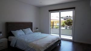 a bedroom with a bed and a large window at Moradia T4 Fernão Ferro in Fernao Ferro