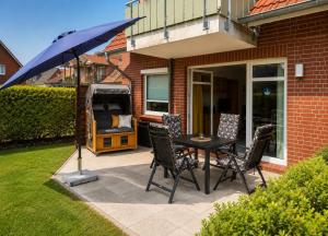 a patio with a table and chairs and an umbrella at FeWo kleine Auszeit in Cuxhaven