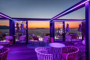 a patio with purple lights and tables and chairs at Hotel Vlora Priam, Affiliated by Meliá in Vlorë