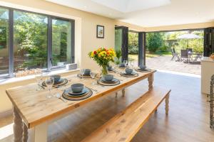 a dining room with a wooden table with glasses and flowers at Saltkettle Sanctuary, Blakeney By Together Travel in Blakeney