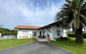a white house with a palm tree and a driveway at Uhalden borda in Saint-Jean-de-Luz