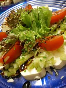 a blue plate with a salad with tomatoes and lettuce at Pension Landhaus Ingrid in Loich