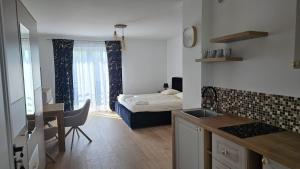 a room with a kitchen and a bedroom with a bed at White Villa in Darlowko