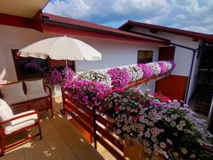 a balcony with flowers and an umbrella on a house at Horse Whispering Ranch apartma in Ilirska Bistrica