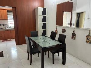 a dining room with a glass table and black chairs at Fairuz Homestay Ipoh in Ipoh