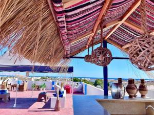a patio with a straw roof and tables and vases at Naama Lofts in Sharm El Sheikh