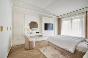 a white bedroom with a large bed and a chair at Apartamenty Topollino in Częstochowa