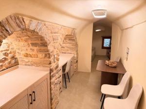 a room with a stone wall and a table and chairs at Luxe Lane Kalamoti in Chios +1 photo
