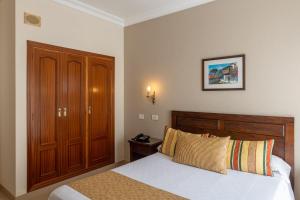 a bedroom with a bed and a wooden cabinet at Hotiday Tenerife Norte in Puerto de la Cruz