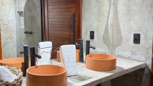 a bathroom with a row of orange buckets on a counter at Exclusive Huts in Gravatá