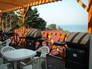 a deck with tables and chairs and a table and a grill at Strawberry Farm Shirasaki in Yura
