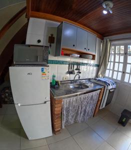 a small kitchen with a refrigerator and a sink at Chale Maresias 1 in São Sebastião