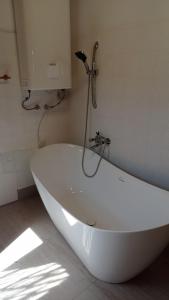 a white bath tub with a shower in a bathroom at Revans teázó apartman- belváros in Pápa +21 photos