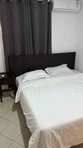 ein großes Bett mit schwarzem Kopfteil und weißen Laken in der Unterkunft Diamond View in Quatre Bornes
