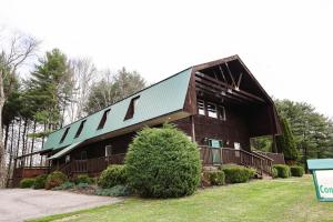 a large wooden barn with a green roof at The Cabins at Pine Haven - Beckley in Beaver