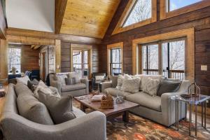 a living room with couches and tables and windows at Shawnee Ridge Lodge in Banner Elk