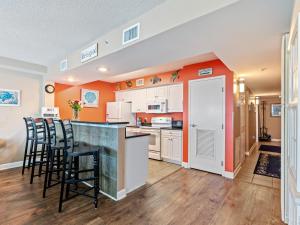 a kitchen with orange walls and a counter with stools at Oceanfront Get Away in Myrtle Beach