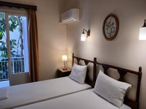 a bedroom with a bed with white pillows and a window at Pension Alkistis in Tolo
