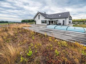a white house with a wooden deck in front of a field at Studio V Šachu-4 by Interhome in Dačice