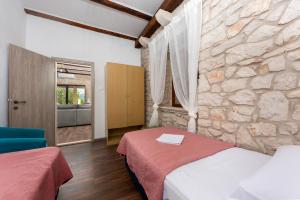 a bedroom with two beds and a stone wall at Authentic Dalmatian Stone House-Kameni dvori in Selca kod Bogomolja
