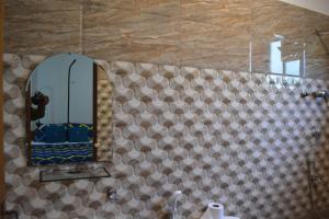 a bathroom with a mirror on a tiled wall at Trinco Eddi Resort in Trincomalee