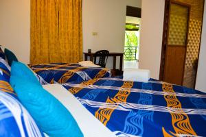 a bedroom with two beds with blue and orange sheets at Trinco Eddi Resort in Trincomalee +15 photos