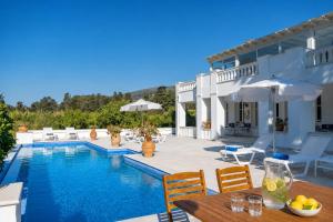 a villa with a swimming pool with a table and chairs at Villa Cypress with Private Pool and Mountain Views in Andros