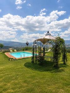 a gazebo in the grass next to a pool at Tenuta Seriole in Poppi