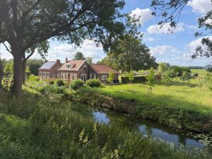 a house with a river in front of it at Het Atelier Schuring - Luxe vakantiehuis 78m2 in Numansdorp