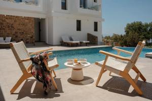 a patio with two chairs and a table next to a pool at Axopetra Boutique Hotel in Agiassos