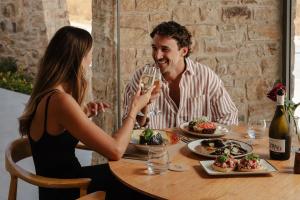 a man and woman sitting at a table with a glass of wine at Axopetra Boutique Hotel in Agiassos