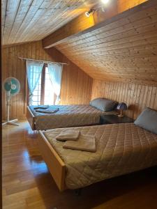 two beds in a room with wooden walls and wood floors at Pancuc Charme & Relax in Gordevio