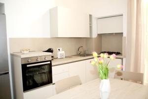 a kitchen with white cabinets and a table with flowers in a vase at Antica Stella in Specchia