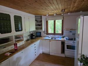 a kitchen with white cabinets and a wooden ceiling at Smaland Trollsjö in Mönsterås