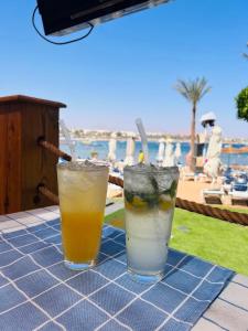 two drinks sitting on a table near a beach at Naama Lofts in Sharm El Sheikh