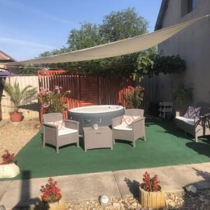 a backyard with a hot tub and chairs and an umbrella at Nyugalom Pihenő in Kisújszállás