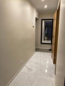a hallway with a white tile floor and a door at Mājīgie Apartamenti Saldū in Saldus