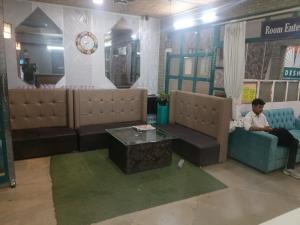 a man sitting on a couch in a living room at Hotel Radhika Palace in Raipur