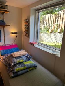 a bedroom with a window and a pile of pillows at Genbrugsfabrikkens Tiny apartment in Holbæk