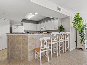 a kitchen with white cabinets and a bar with white stools at Crescent Beauty in Myrtle Beach