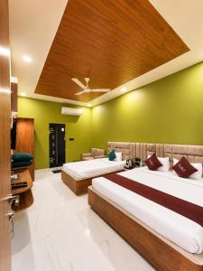 two beds in a room with green walls at Hotel Asha Palace By Basotel in Deoghar
